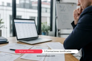 Responsable de empresa revisa documentos de presupuesto, ROI e itinerario formativo sobre una mesa de oficina con un portátil abierto al fondo.