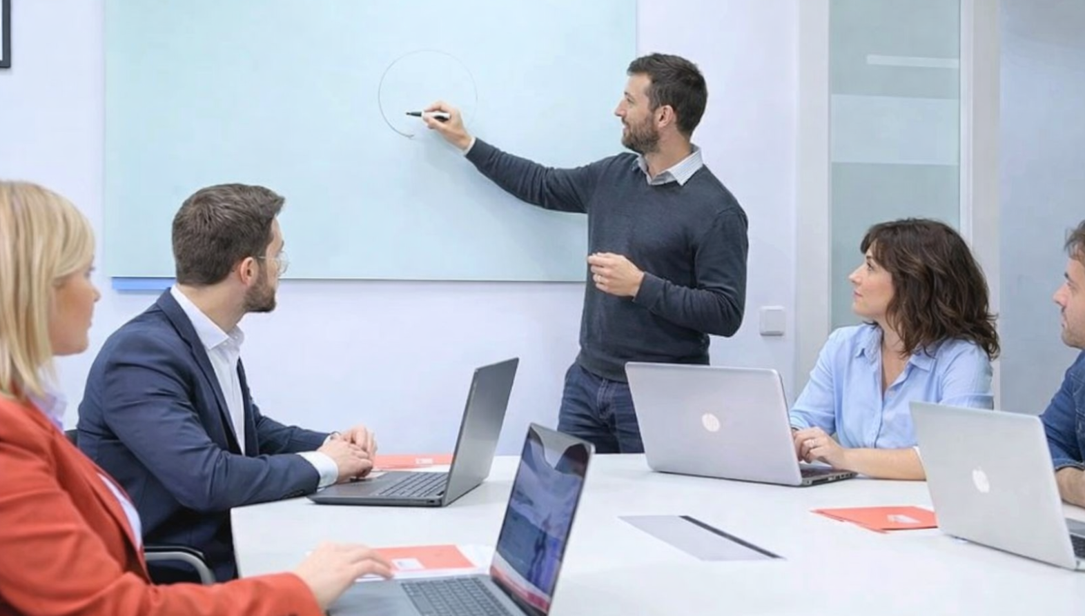 Formador explicando en pizarra durante sesión de formación en empresa